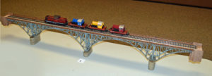 Bridge constructed from 5 Faller kits by Mitch with a German V212 Diesel pulling three flatcars KOEF Diesel loads