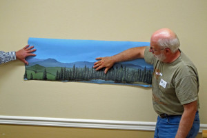 Al Carter showing a backdrop painted on the backside of sheet vinyl flooring